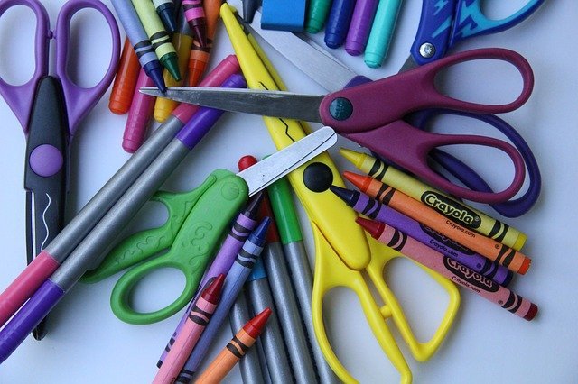 crayons and scissors in pile on gray background