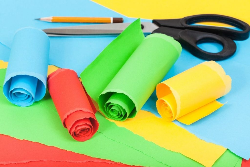 Different colored cardstock papers in rolls with pencil and scissors - paper crafts for kids