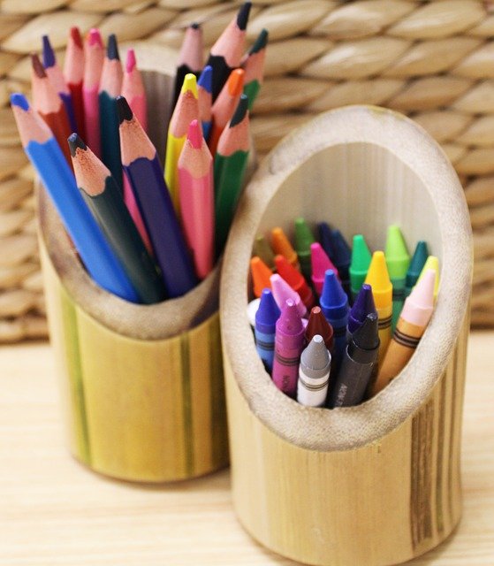 colored pencils and crayons in bamboo cups in front of basket 