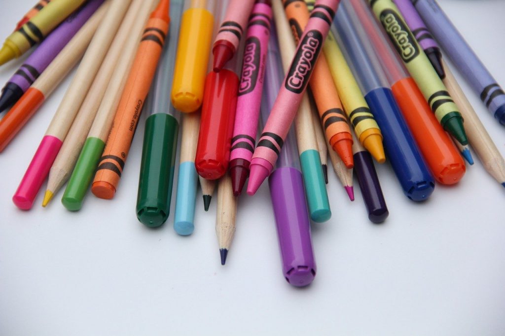 Pile of pencils, crayons and markers on white desktop