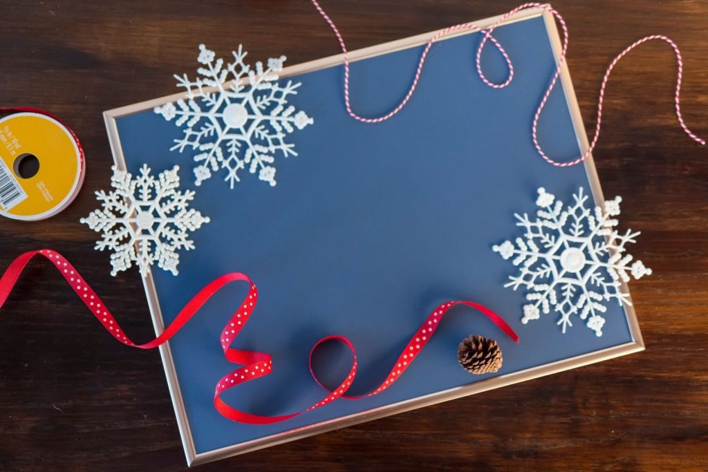 White snowflakes and red ribbon on chalkboard and wooden table - winter crafts for tweens